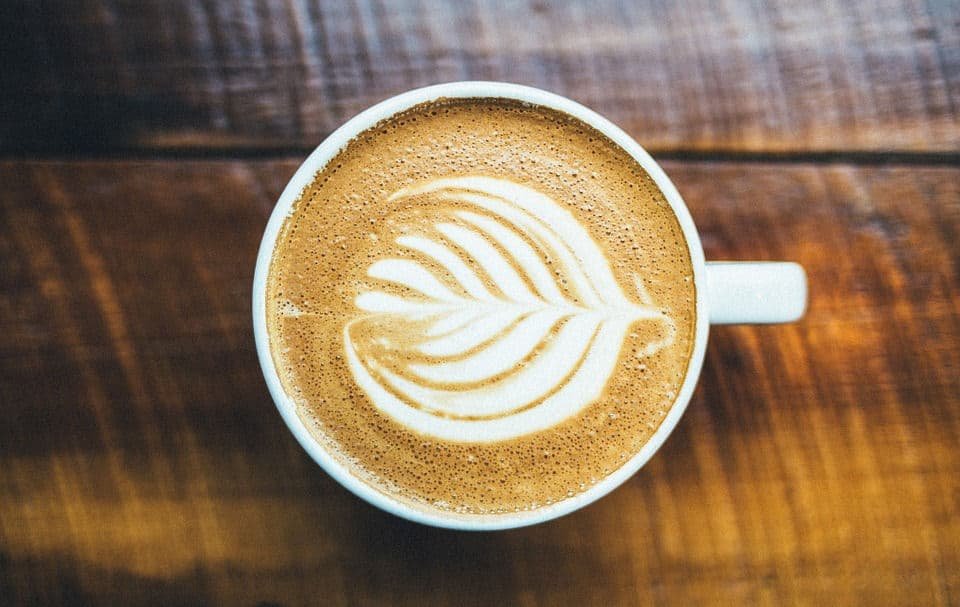 a coffee mug with coffee and a leaf design...