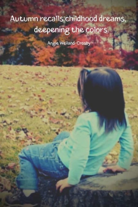 a picture of a little girl on a stump with autumn trees...